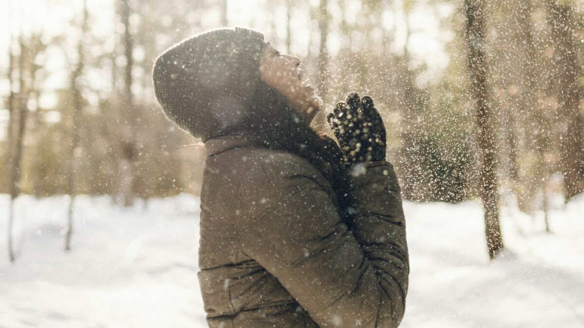 ダウンを着た女性が雪の中笑っている様子