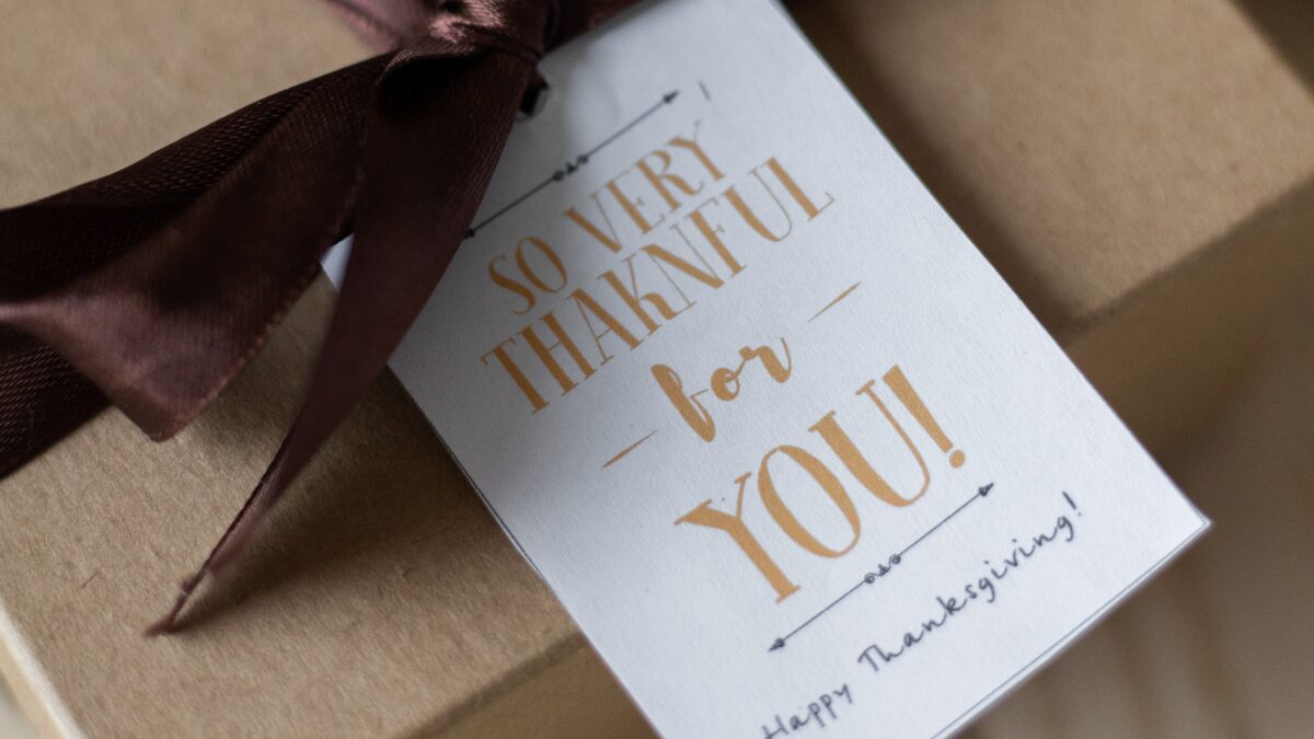 プレゼントにブラウンのリボンとメッセージカードでラッピングしてある画像