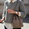 グレージュ色のミニマルなバッグを持っている女性