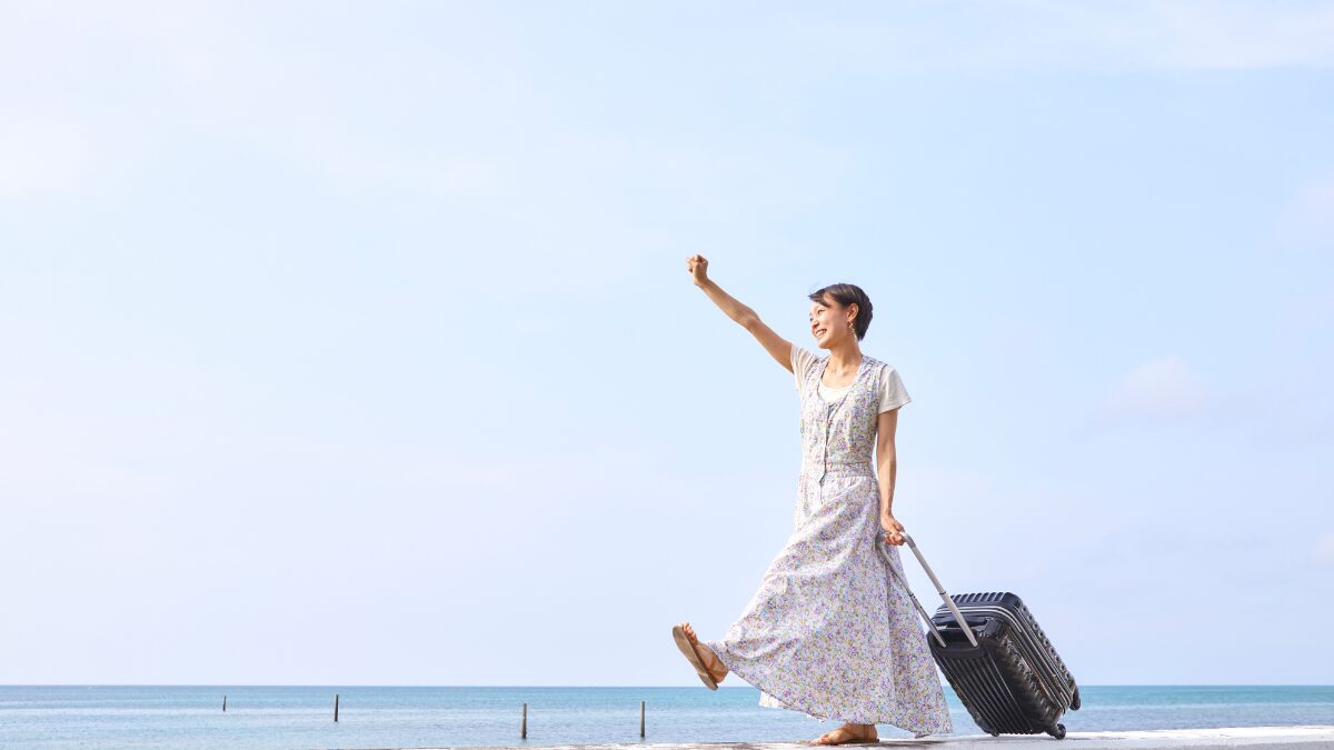 スーツケースを持って元気よく腕を振り上げて歩く女性の様子