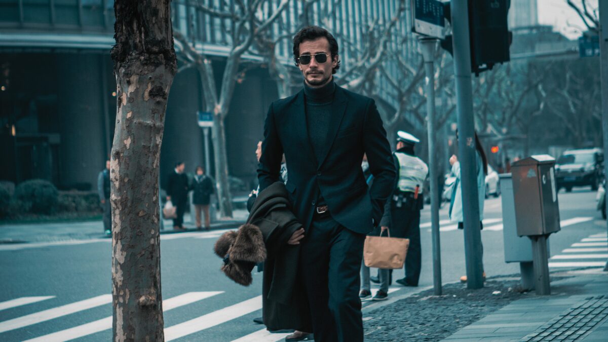 英国紳士風の男性が歩道を歩いている様子。