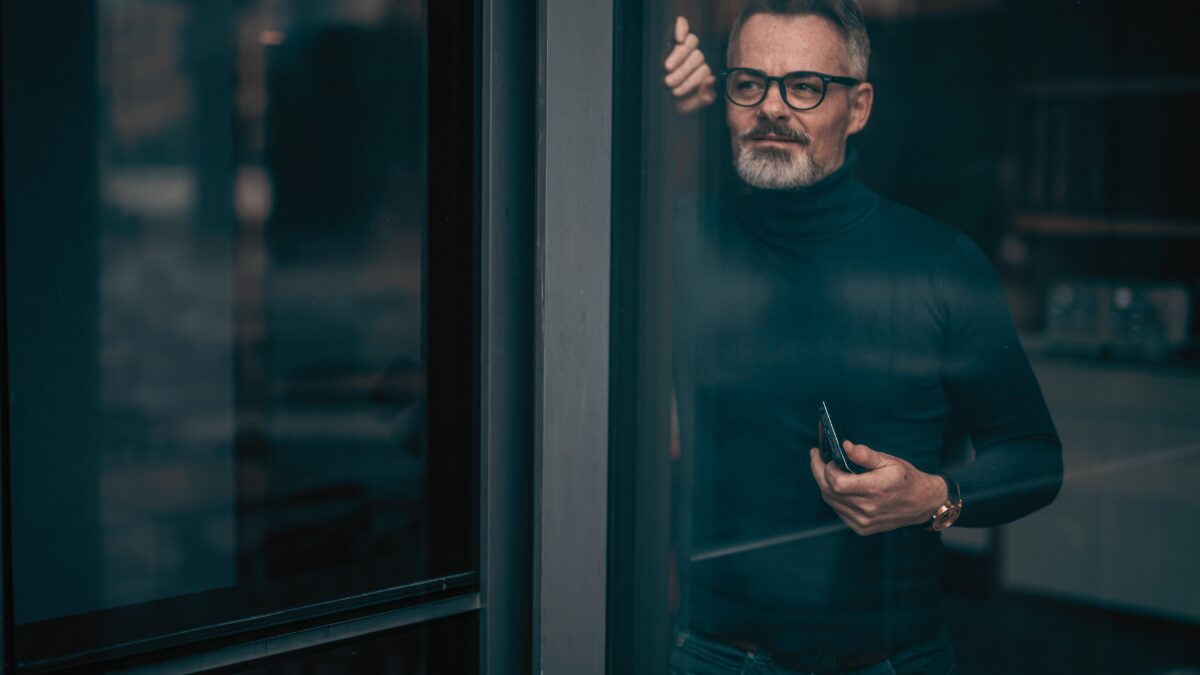 60代の男性のポートレート。ダンディーな英国紳士風の男性が窓の外を眺めている様子