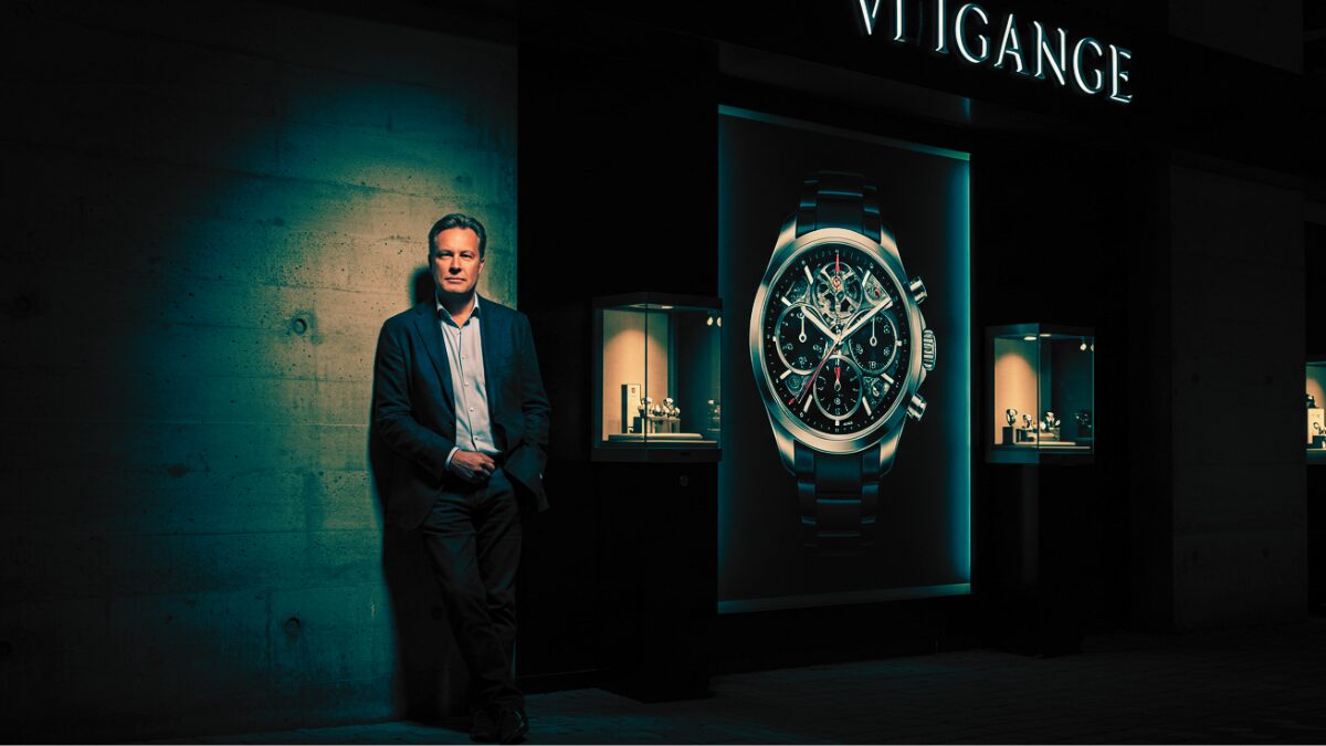 ダークで洗練された雰囲気、時計ブランドの広告が映り込むショーウィンドウ、そして落ち着いた表情の紳士