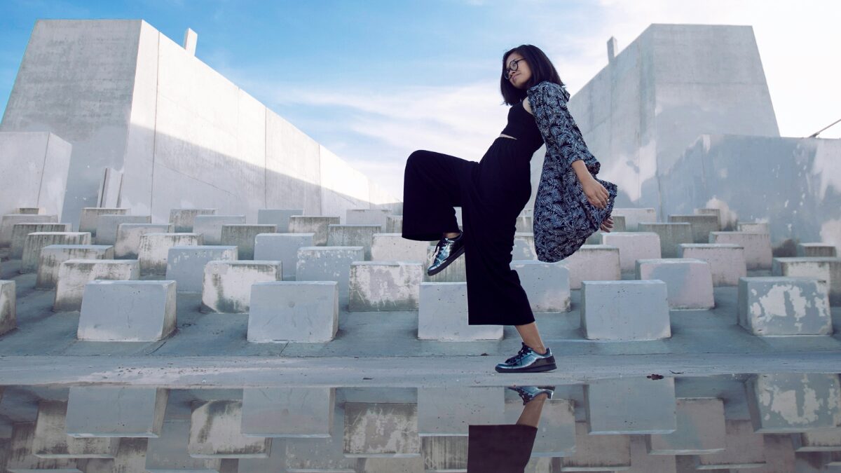 片足を上げて楽しそうに歩く女性。モダンなロケーション