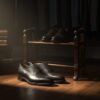 A moody, cinematic shot of a gentleman’s dressing room with dark oak flooring, leather-bound books, and a half-open wardrobe of tailored suits. On a vintage shoe rack, a pair of John Lobb cap-toe Oxfords are perfectly aligned. Warm morning light filters through a window, casting soft shadows. The mood is private, luxurious, and quintessentially British.