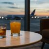 窓際のテーブルに2人分のドリンク。外には飛行機がぼんやり見える。