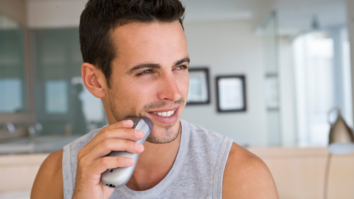 電気シェーバーで髭を剃っている男性