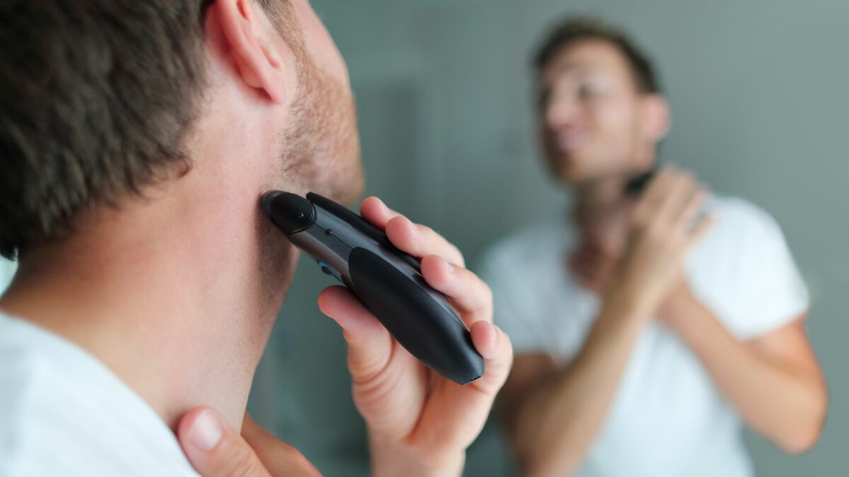 鏡の前で髭を剃る男性の後ろ姿