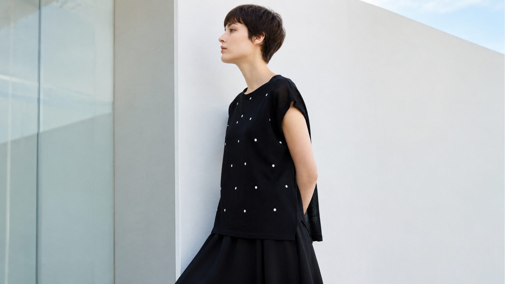黒のドット柄ノースリーブトップスと黒のスカートを合わせた、大人女性の夏向けビアズリー風モノトーンコーデ