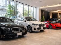高級車レンタカーの比較をイメージした写真、ショールームに並ぶ複数の高級車、黒い高級セダン、白いSUV、赤いスポーツカー、清潔で高級感のある空間、広告写真風